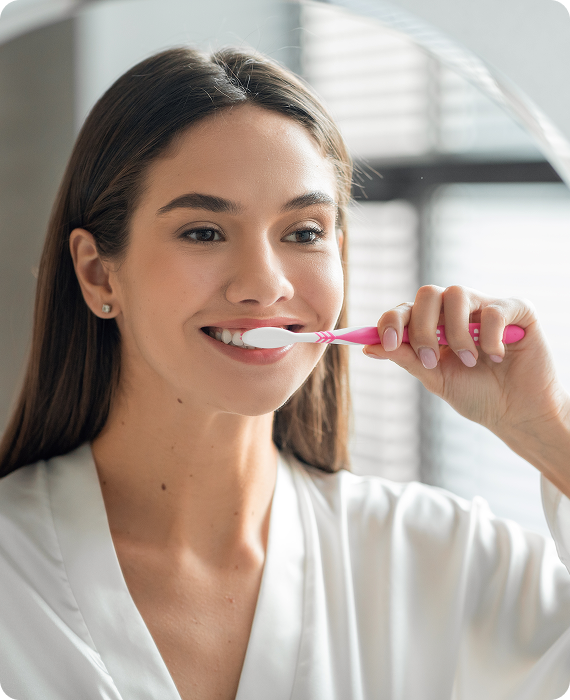 Smiling woman looking into mirror brushing her teeth smoothly